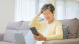 Older Asian woman looking at her phone and seeming confused, photo by PonyWang/Getty Images