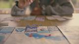 Closeup of a game on a table, with a person in the background, photo by janiecbros/Getty Images