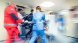 Paramedics and a nurse pushing a gurney in a hospital, photo by vm/Getty Images