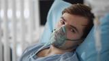 Man with oxygen mask on his face lying in a hospital bed, photo by nimito/Adobe Stock