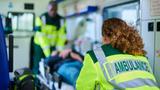 Two emergency medical staff moving a person on a stretcher into an ambulance, photo by sturti/Getty Images