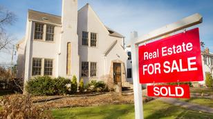 A large house with a for sale sign marked sold, photo by YinYang/Getty Images