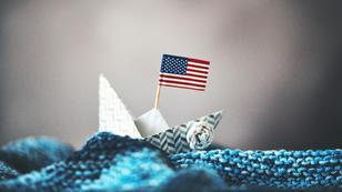 Paper boat with American flag on fabric waves, photo by CatLane/Getty Images