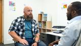 Doctor sitting with a male patient in a doctor's office, photo by SolStock/Getty Images.