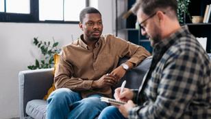 Male counselor asks a man questions while they both sit on a couch, photo by  Brothers91/Getty Images