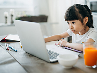 Young girl attends virtual class on her laptop computer. 