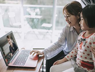 Mother and daughter using laptop computer for a telehealth pediatrician appointment. 